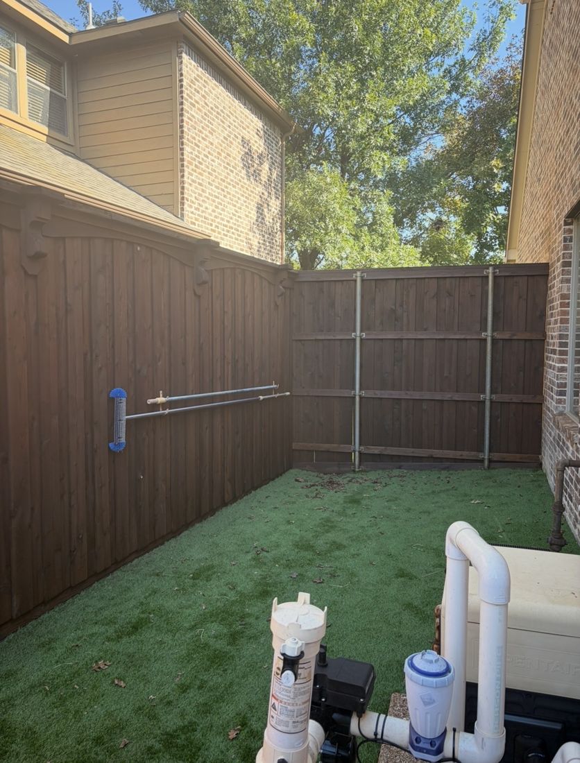 Fence corner with arched top trim over artificial turf