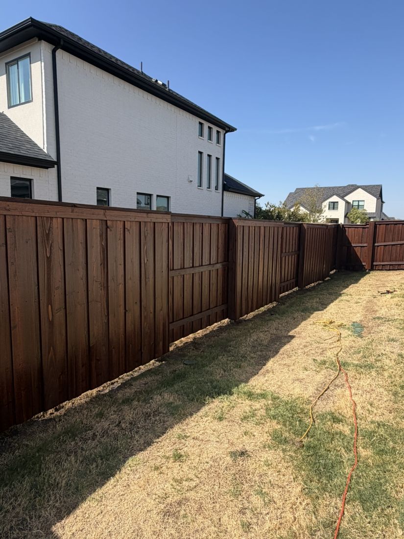 Board-on-board fence in a dark walnut stain along a backyard
