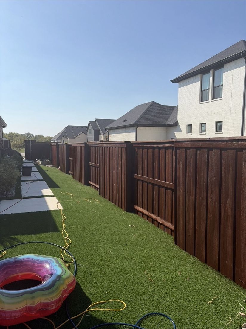 Fence stained reddish brown beside artificial turf