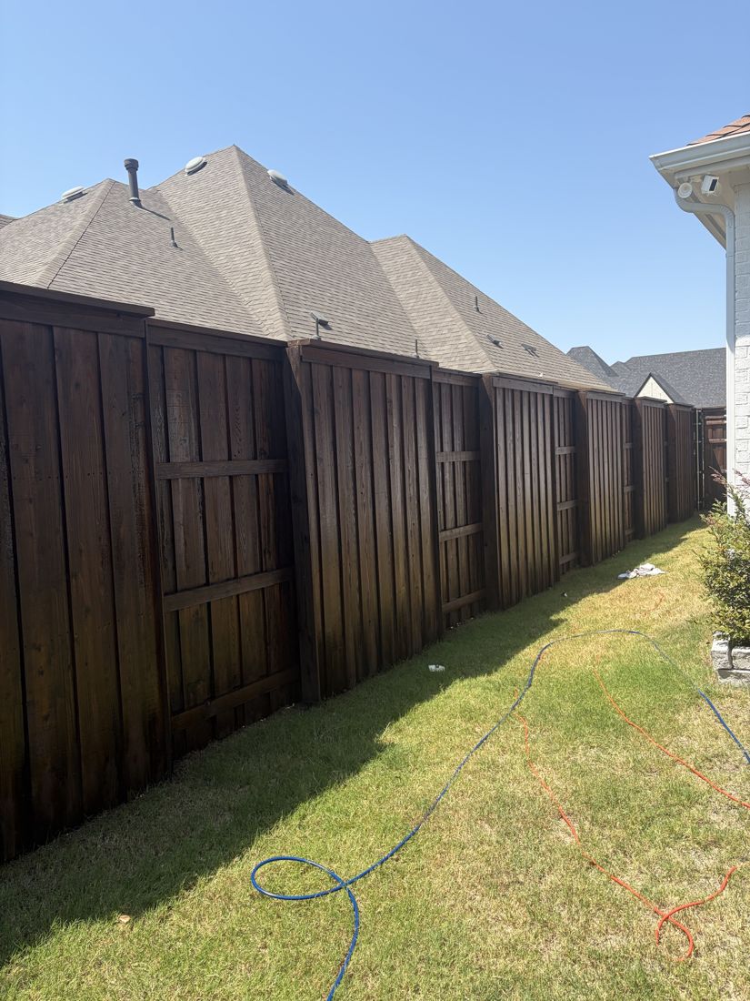 Tall dark stained fence running the length of a backyard