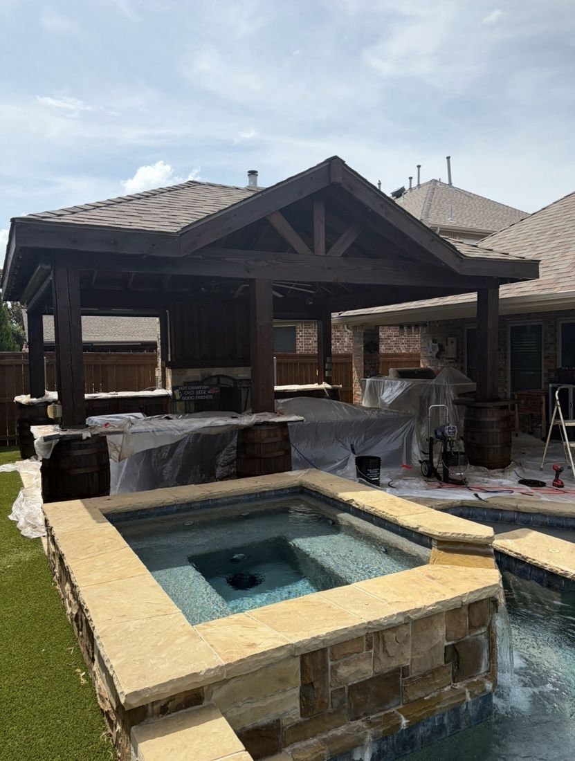 Dark stained cedar pergola over an outdoor kitchen beside a pool