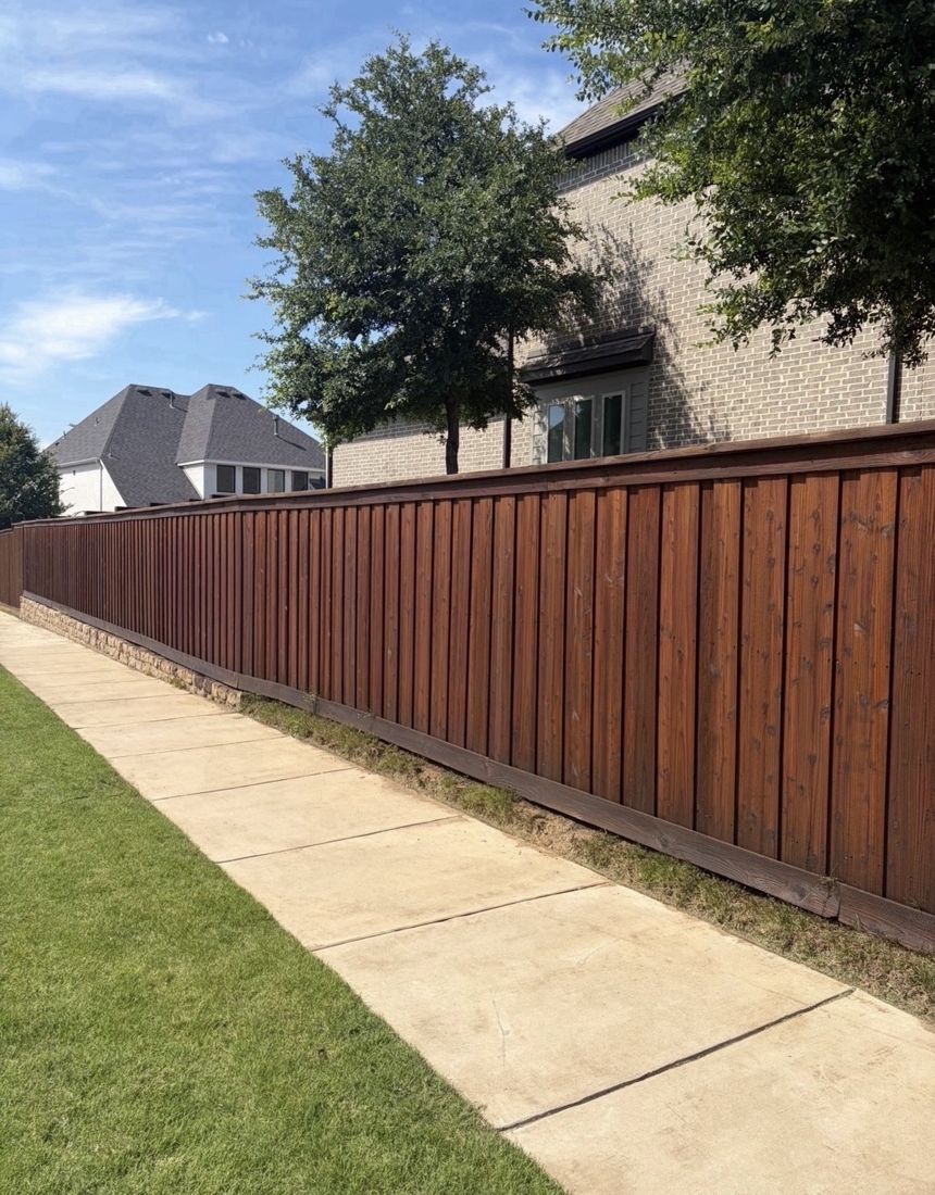 Long capped fence along a sidewalk stained reddish brown